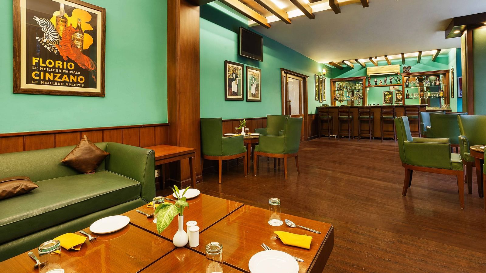 A sofa paired with a wooden table, elegantly set with plates and cutlery, alongside neatly arranged tables and chairs in a bar setup