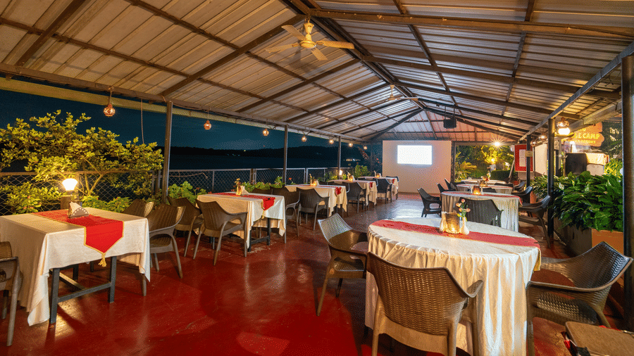 Image a dining area with a slanted roof and tables and chairs at Coorg Jungle Camp Backwater Resort, Kushalnagar.