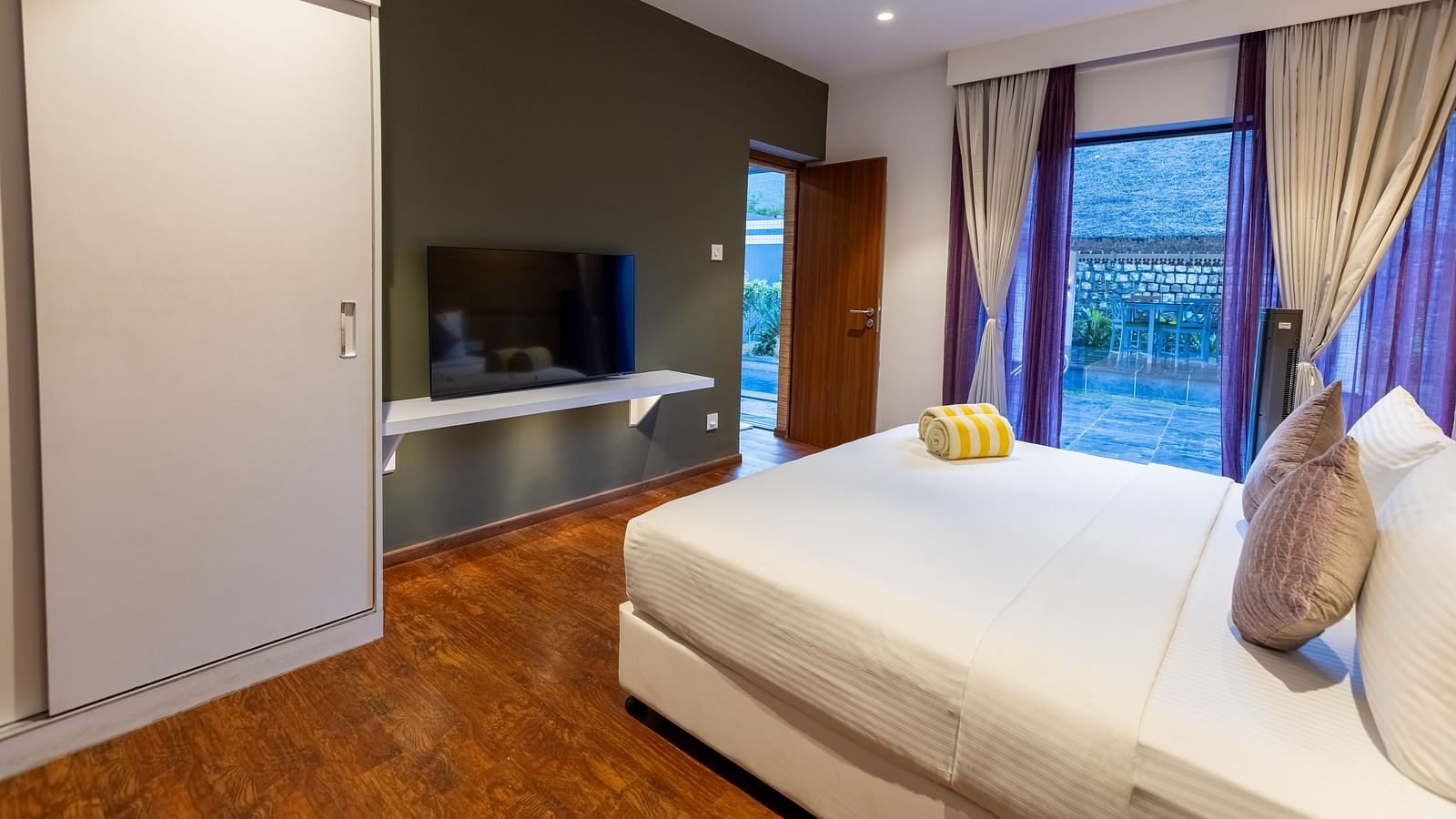 image featuring a plush double bed placed in front of a wall mounted television at the luxury villa - Darza Resorts