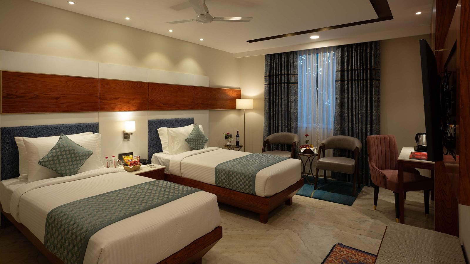 An image of a bedroom with twin beds, sofa, chair, and table