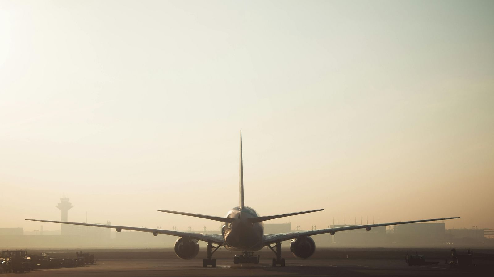 Rear view of a passenger aeroplane on an airport runway under a bright, clear sky.