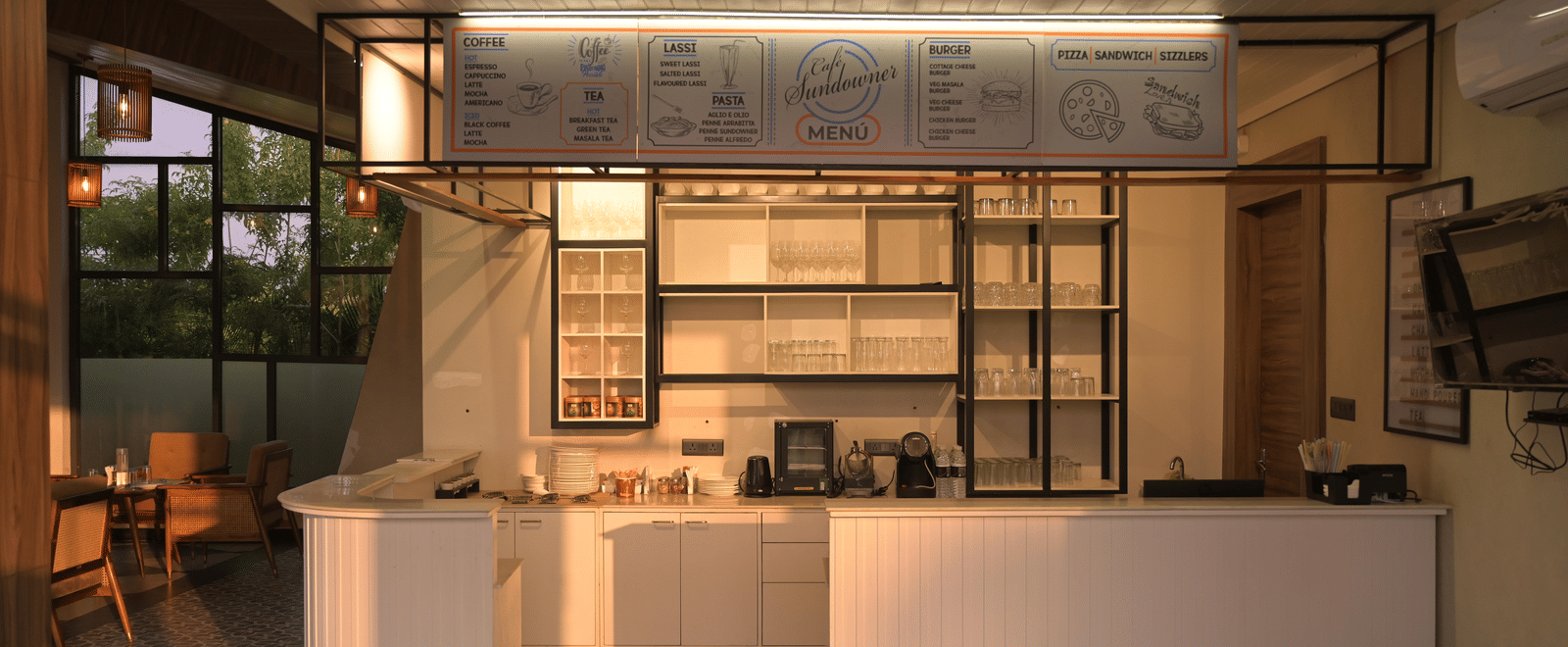 A modern cafe counter with clean lines, open shelving, and warm ambient lighting at Hotel Sonar Bangla Mayapur.