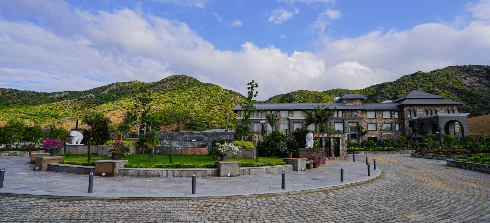 A long view of the main resort building from the driveway, showcasing its modern architecture and the landscaped grounds.