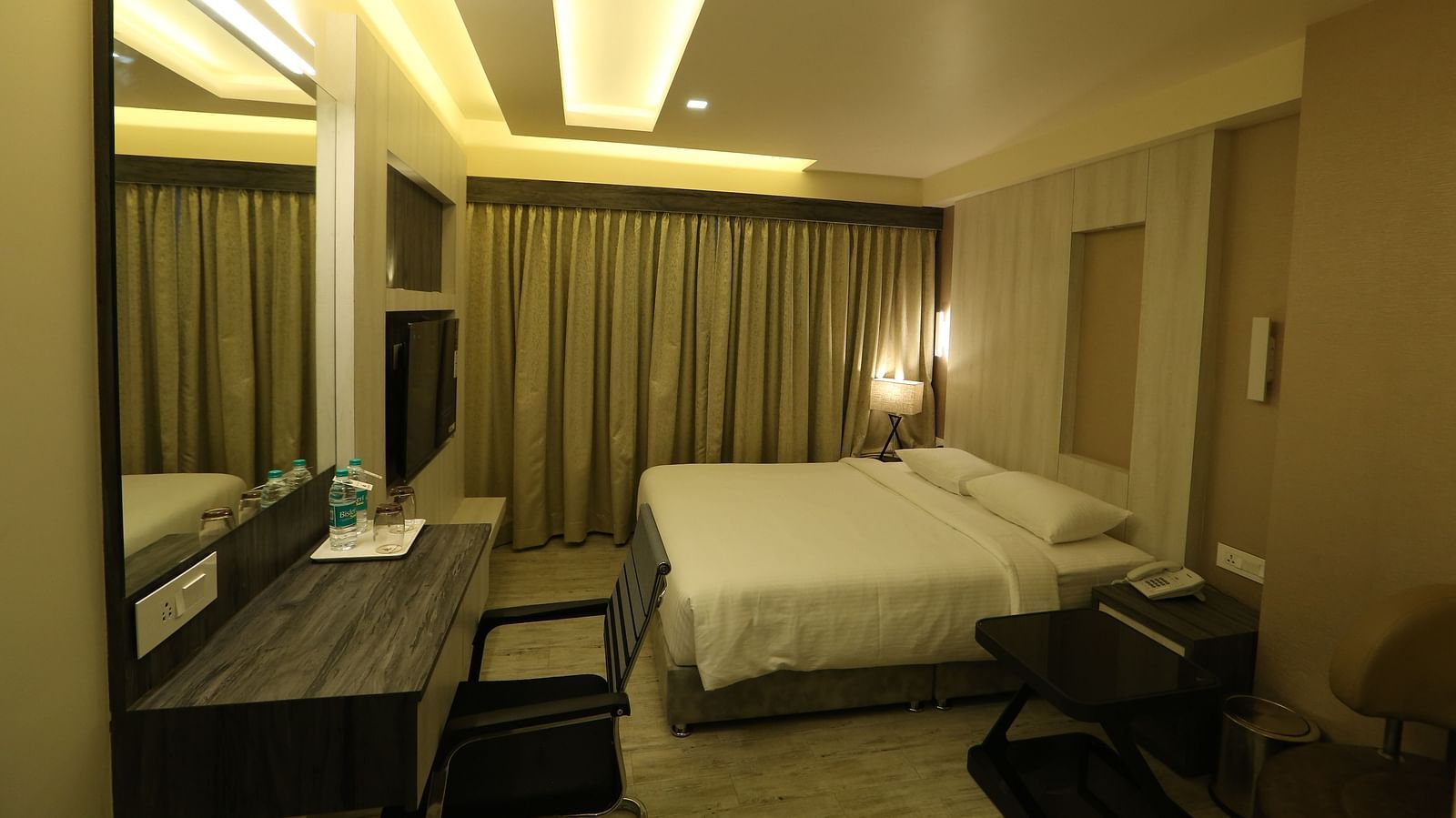 Premium Room featuring a king size bed, desk with a mirror, chair, and ambient lighting, showcasing the room's layout and decor - TGI SPS Grand, Coimbatore