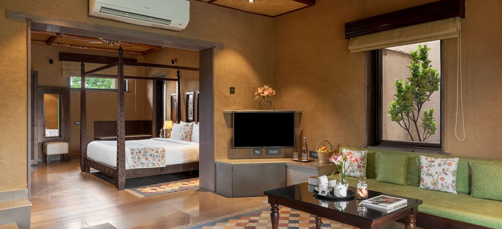 A cosy living area featuring a corner sofa and a dining table at Aamaghati Wildlife Resort.