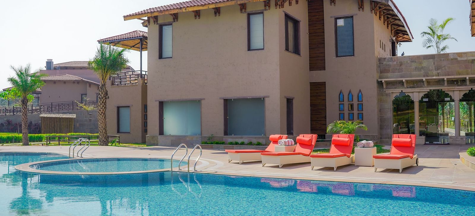  A resort building overlooking a large, inviting swimming pool with sunbeds at Aamaghati Wildlife Resort.