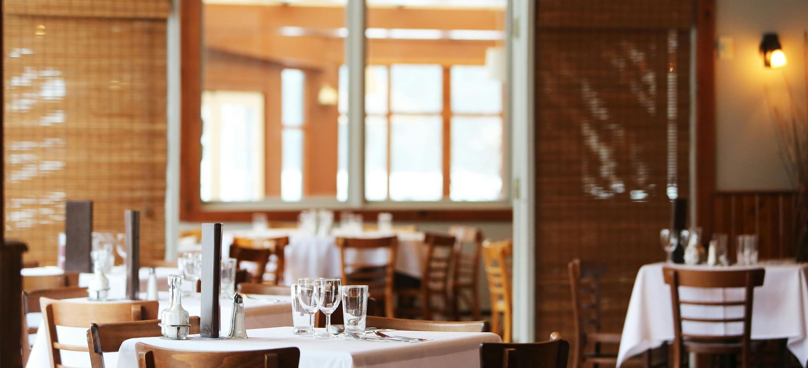 A restaurant interior with tables set with white tablecloths and chairs.
