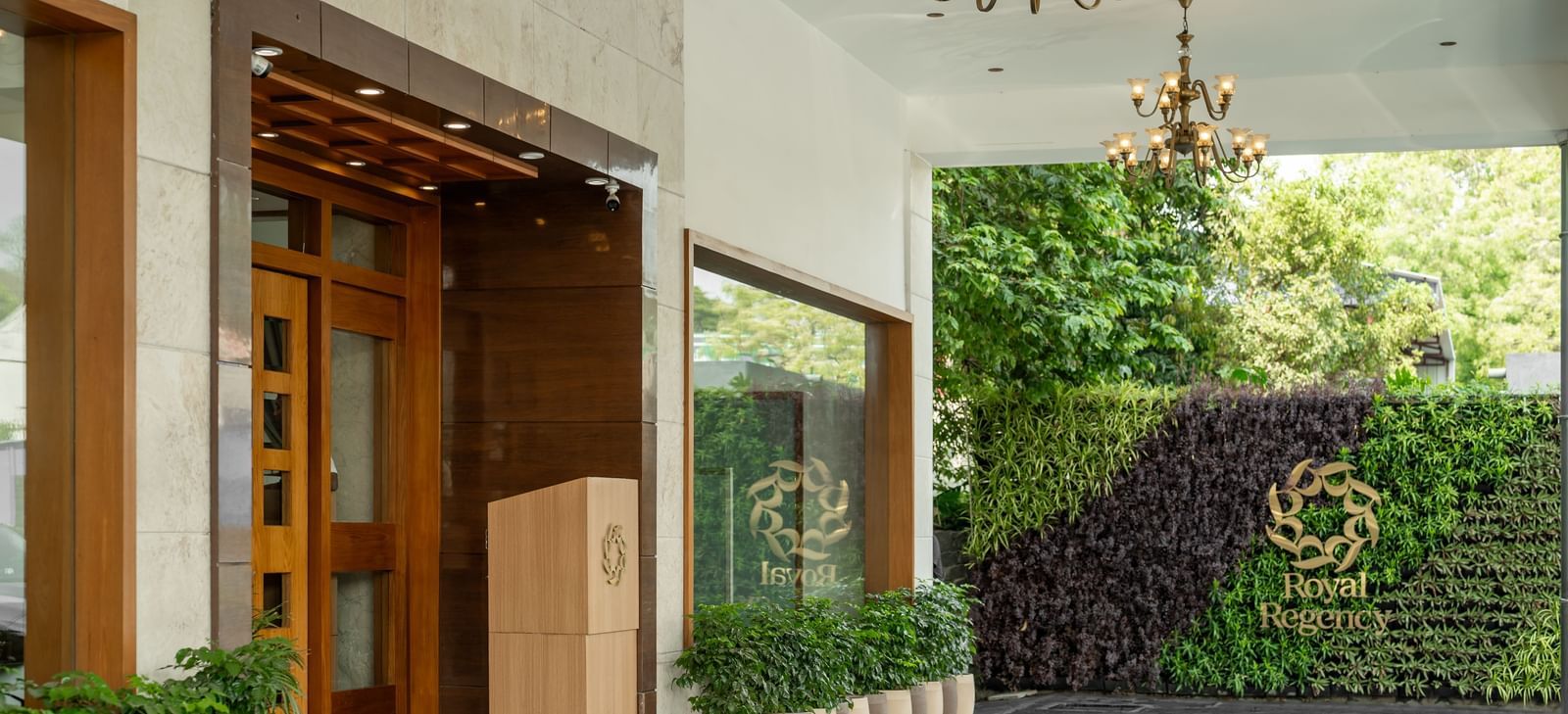 Hotel Royal Regency Chennai entrance with glass doors, greenery, and chandelier