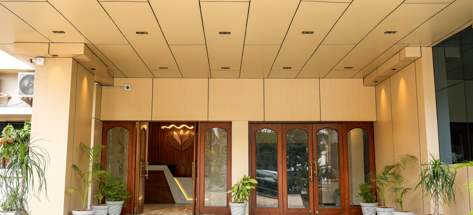 Hotel entrance with glass doors and potted plants at Pravasa Hotel, Kolhapur.