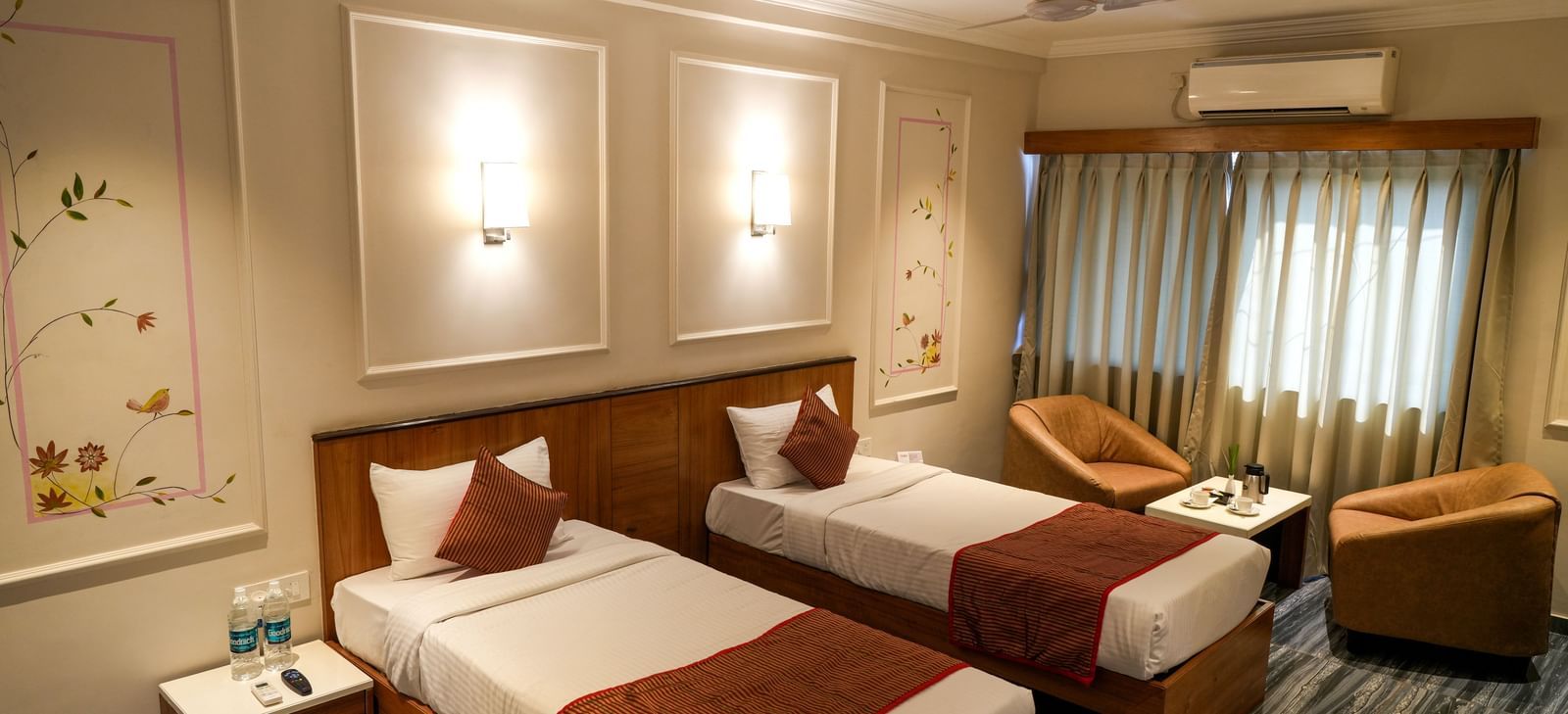 Comfortable twin room with two neatly arranged beds and cosy seating at Pravasa Hotel Kolhapur.