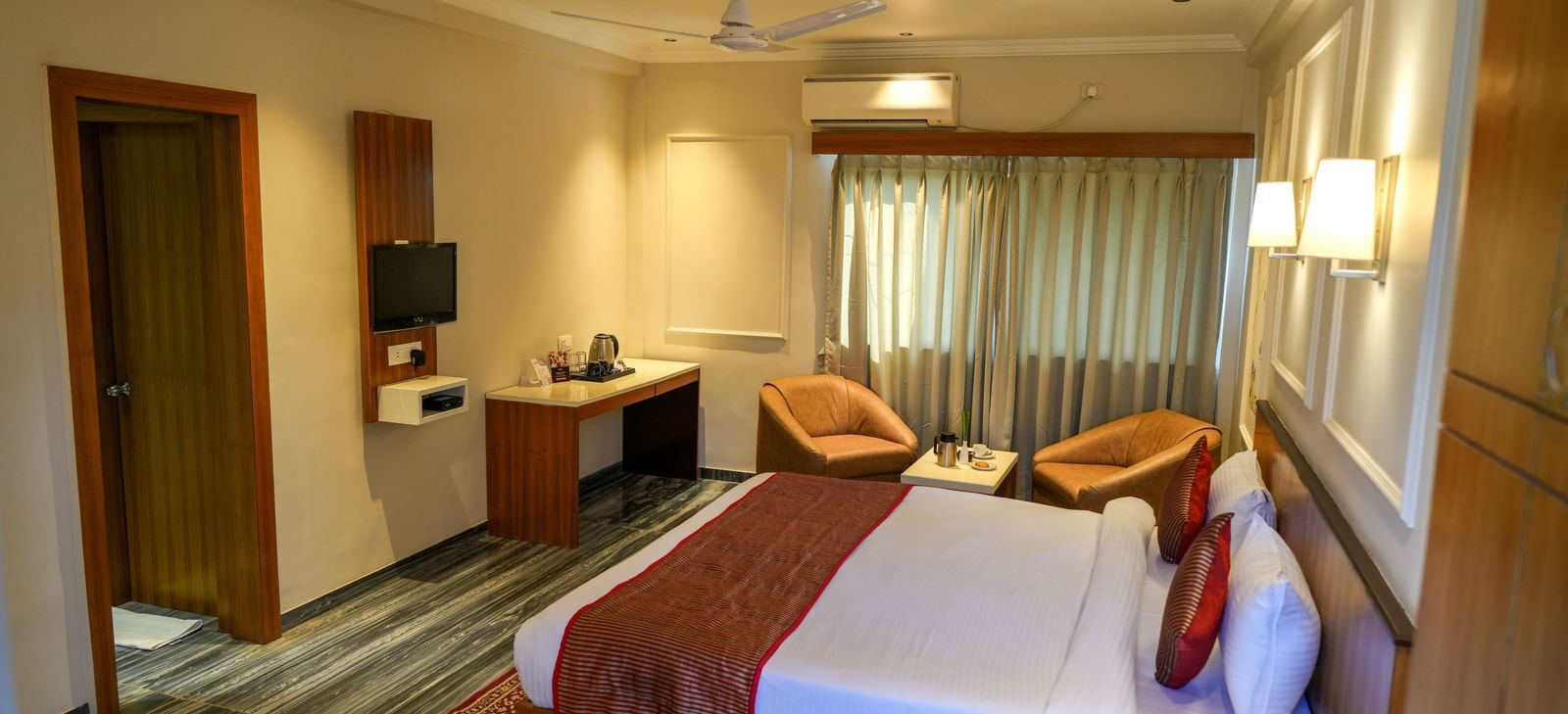 Well-appointed guest room with a king-size bed and seating for relaxation at Pravasa Hotel Kolhapur.