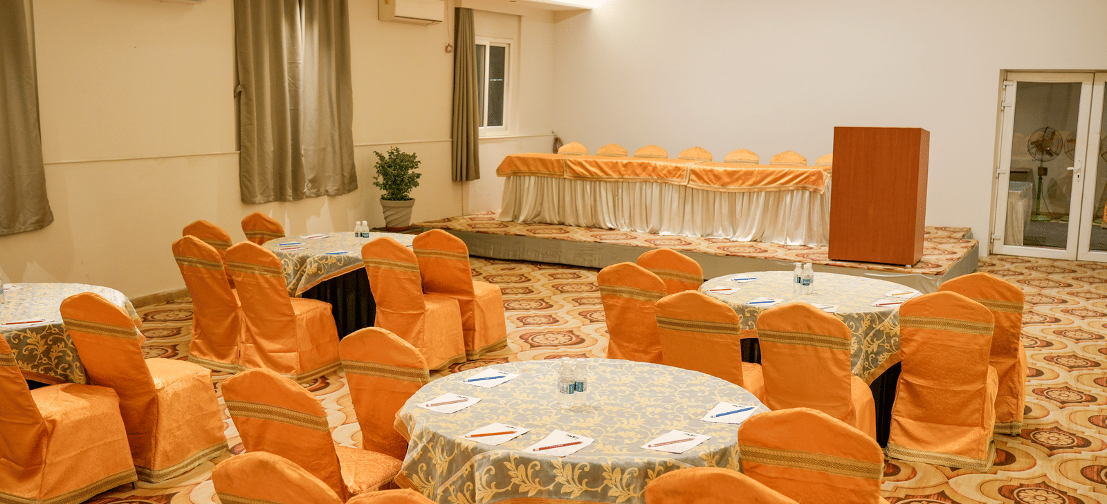 Banquet hall with round tables and chairs at Pravasa Hotel, Kolhapur.