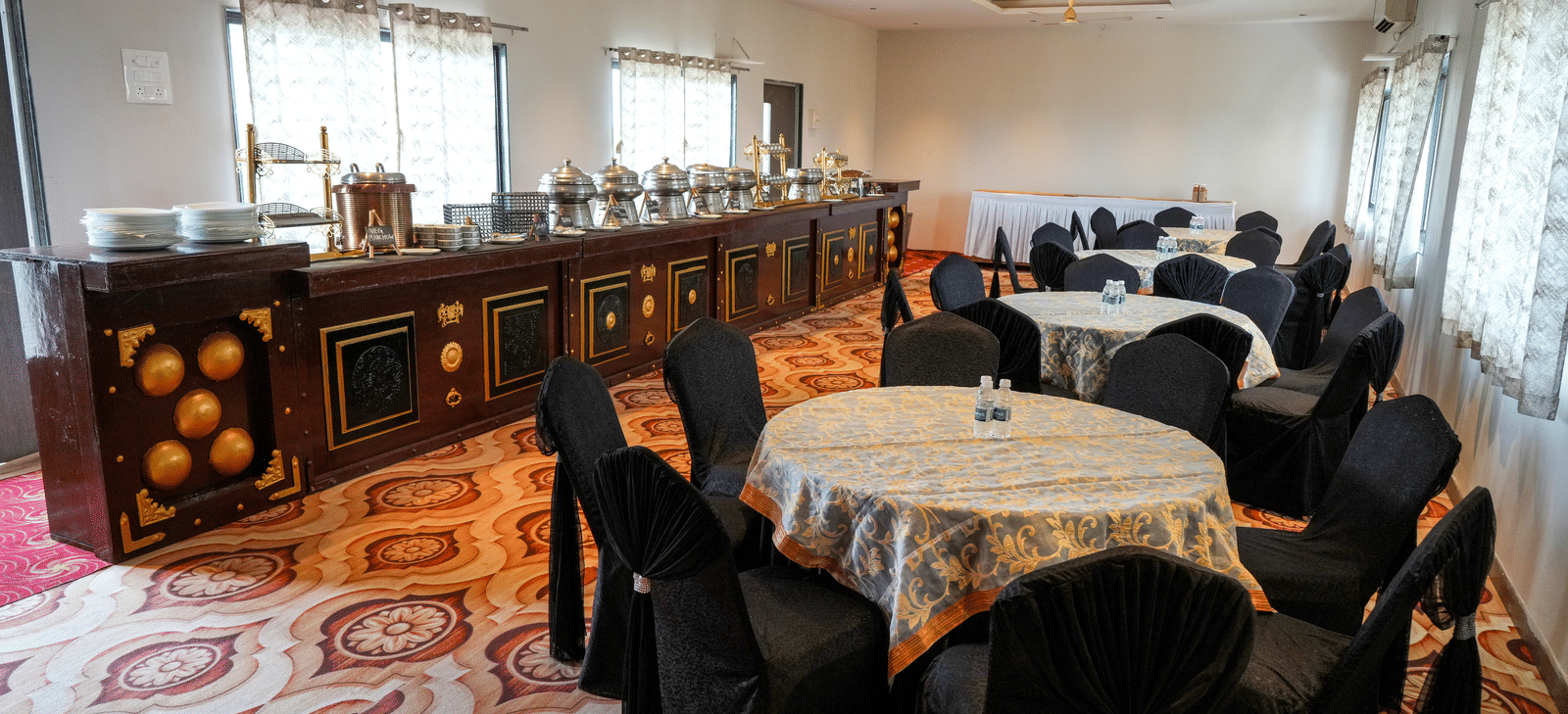 Dining area with tables and buffet counter at Pravasa Hotel, Kolhapur.