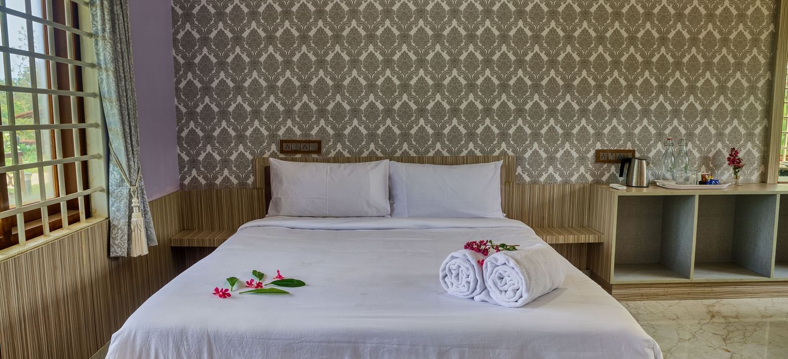  A bedroom with a large white bed against a textured, light-coloured wall, with a small bedside table, ready for guests. - Vintage Trails by Ilara
