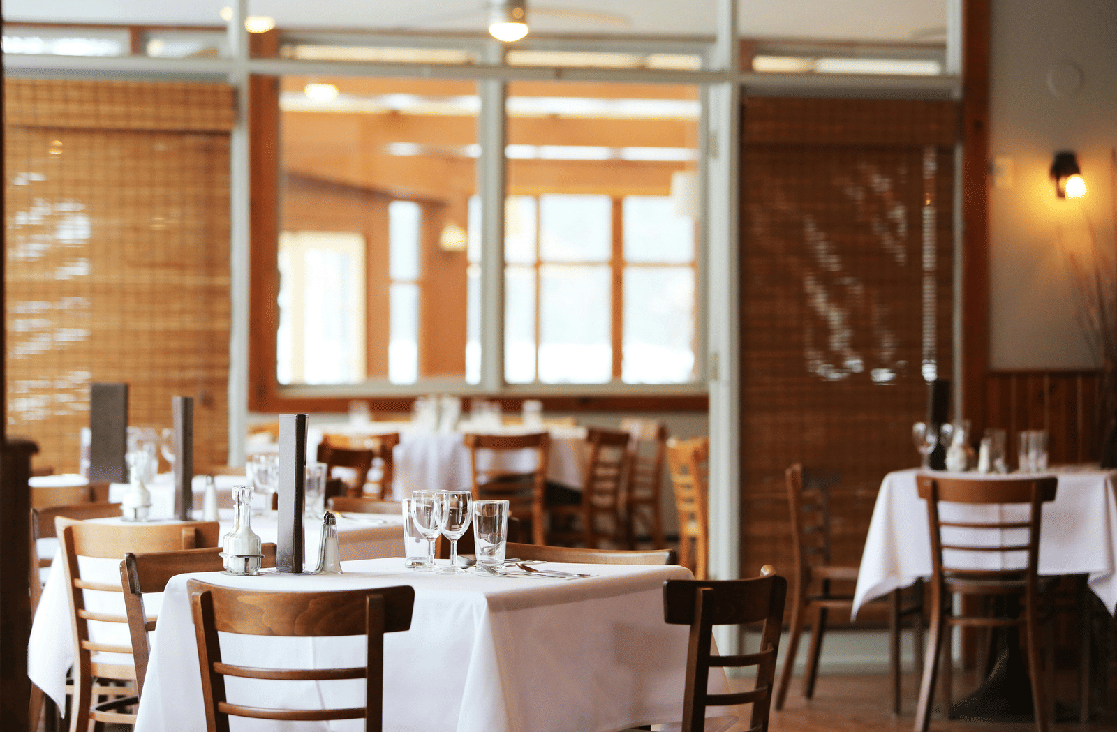 Elegant restaurant interior with neatly set tables, wooden chairs, and soft ambient lighting.