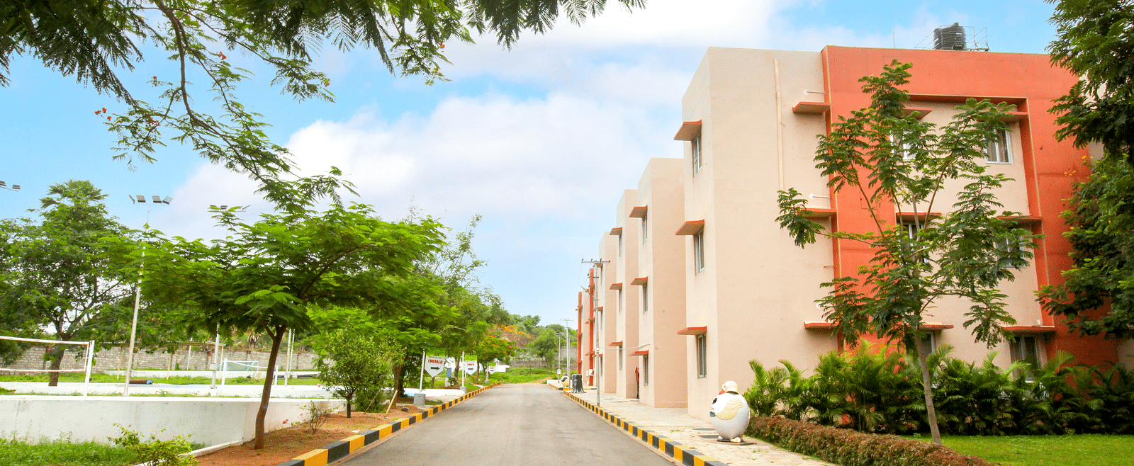 A view of Greens Inn by a road, surrounded by trees - Convenient Location in Hyderabad.