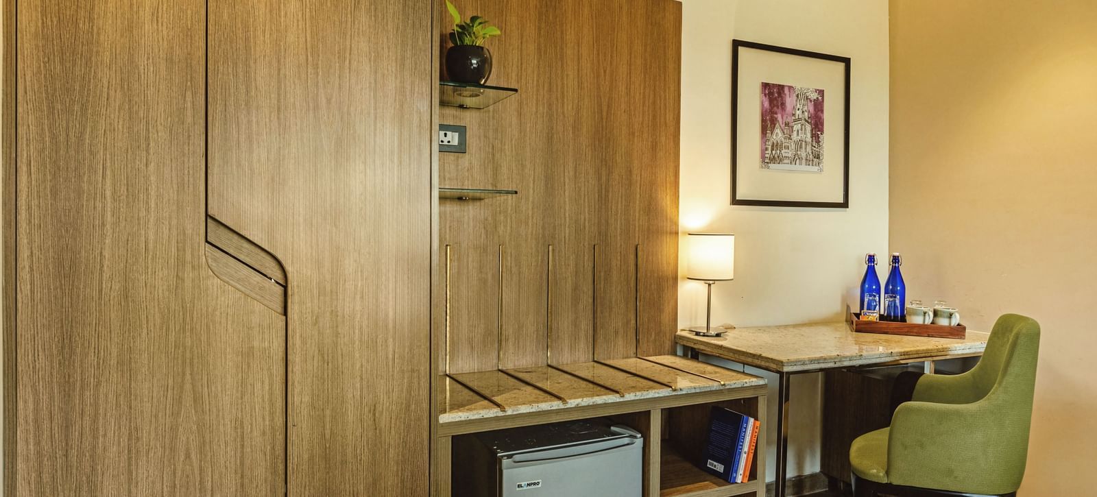 A room at Mango Hill Central, Chennai, with wooden cabinets, a desk, and a small refrigerator.