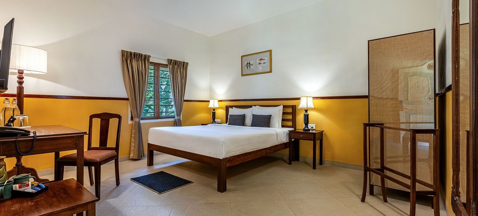 Comfortable bedroom in Pondicherry featuring a double bed, a writing desk, chairs, and a full-length mirror | Mango Hill Shallow Beach Resort ECR