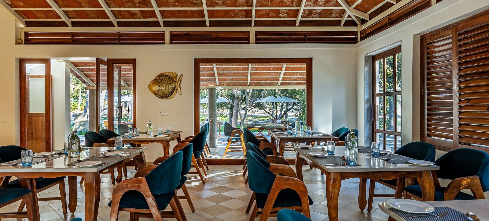 Image of a restaurant by the beach with wooden interiors blue chairs, and a high, patterned ceiling | Mango Hill Shallow Beach Resort ECR