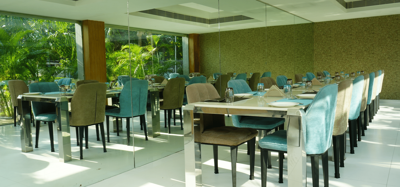 Bright indoor dining section with aligned tables and chairs surrounded by natural light - Grande Bay Resort & Spa, Mamallapuram
