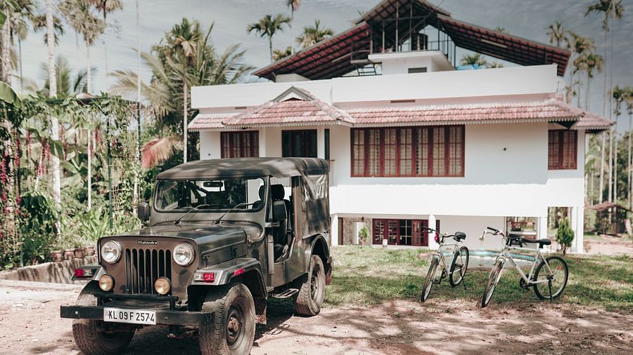a Jeep and two bicycles standing in front of the Facade of Ananda Holiday Home, Wayanad