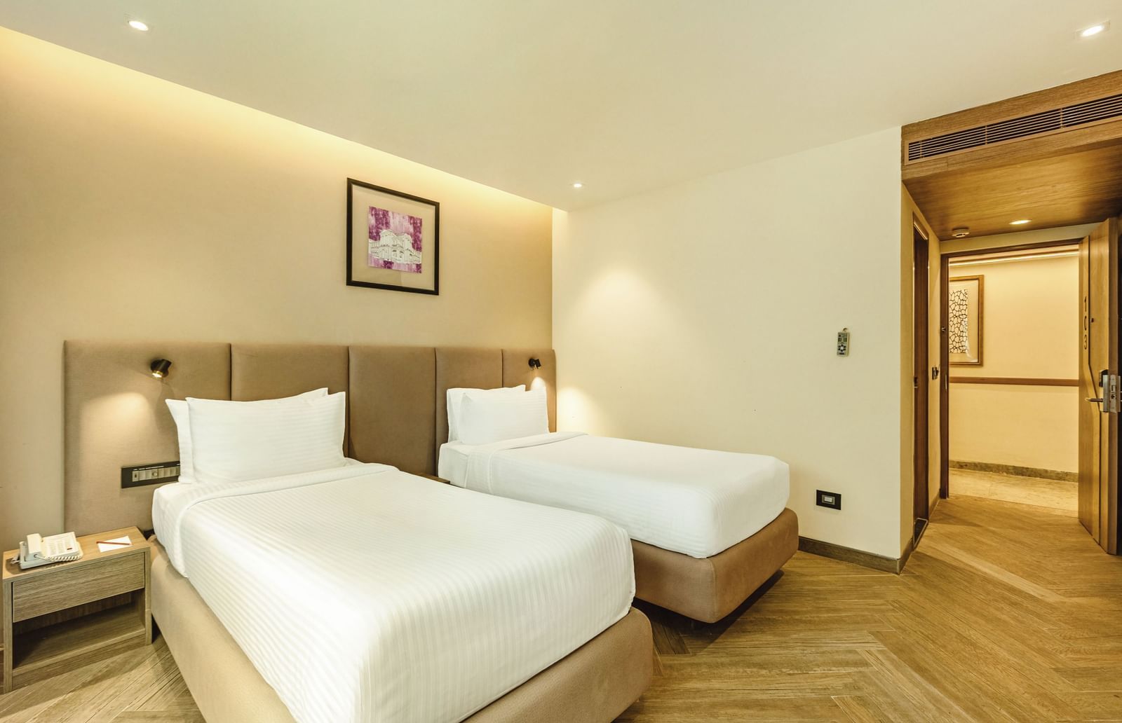 A twin-bedded room with a television and a desk, seen from an angle, at Mango Hill Central, Chennai.