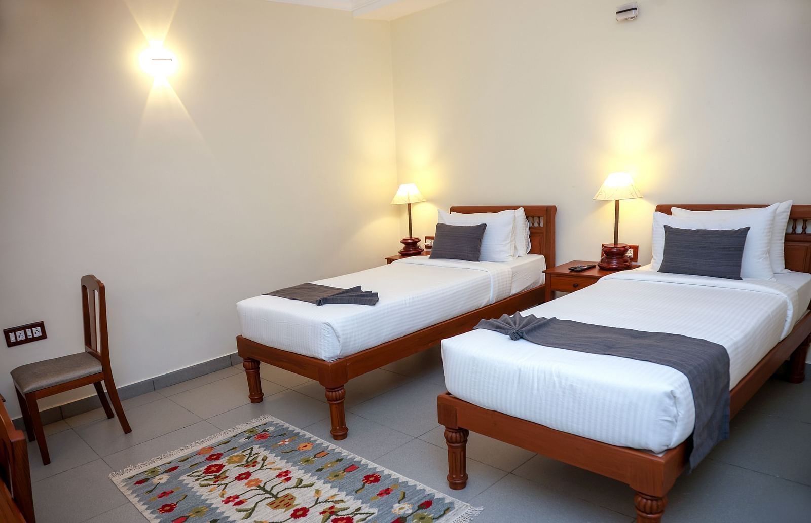 Twin beds and a chair in a room  |Mango Hill La Serene, Pondicherry
