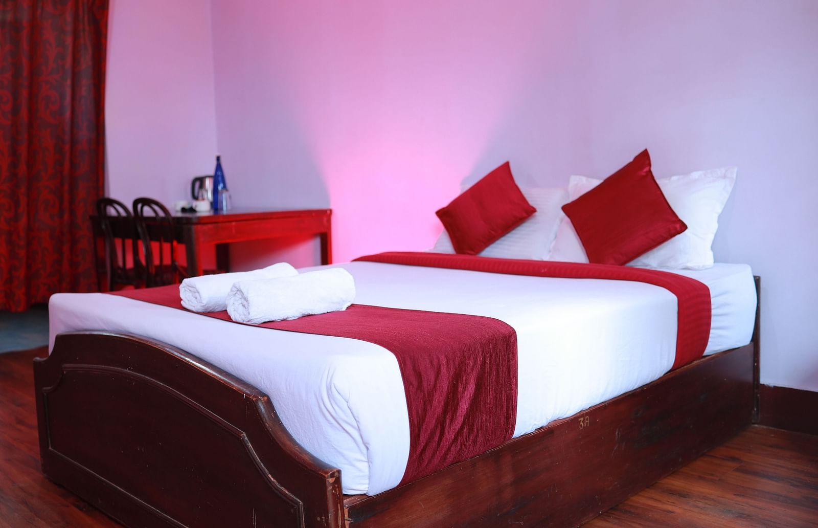 A double bed with red runner and pillows inside one of the rooms  | Mango Hill Shola, Ooty