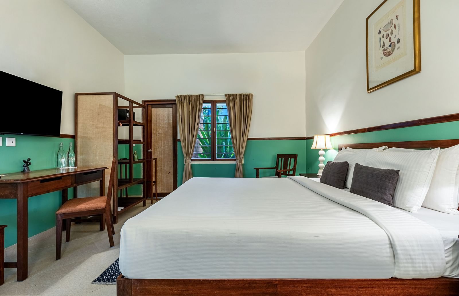 Spacious bedroom featuring a large bed, a desk with a chair, and a television on the wall | Mango Hill Shallow Beach Resort ECR