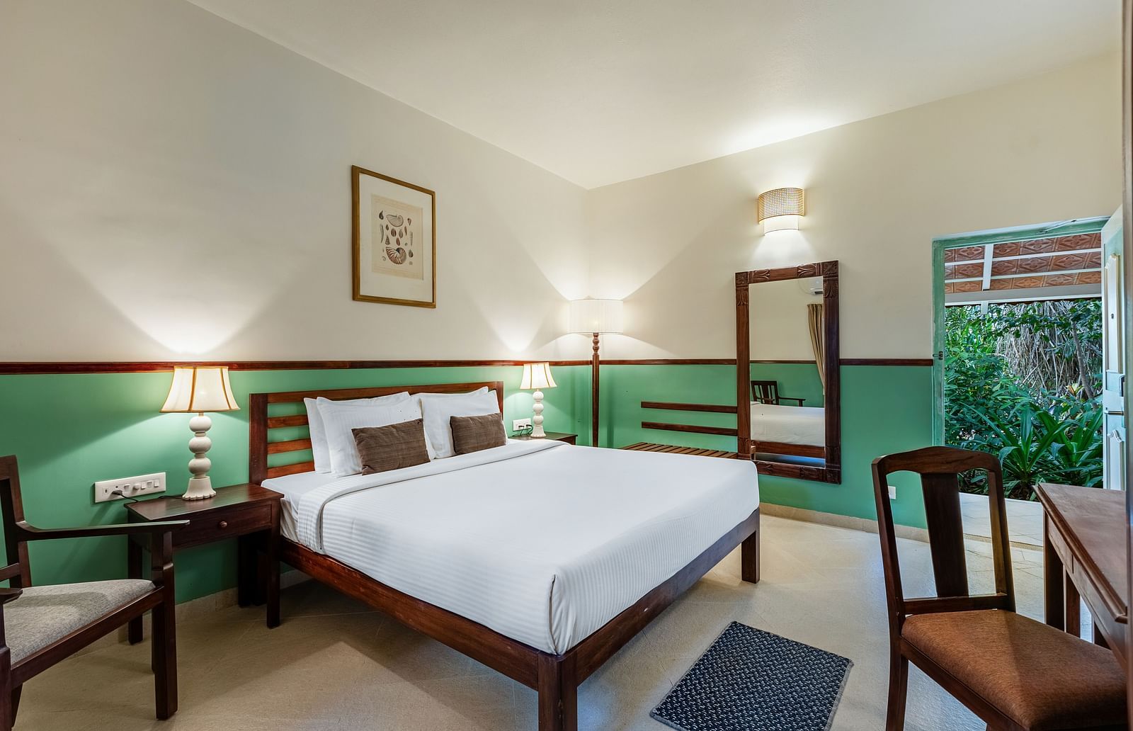 Comfortable bedroom with a wooden bed frame, white linens, bedside lamps, a framed picture, and a window with draped curtains | Mango Hill Shallow Beach Resort ECR
