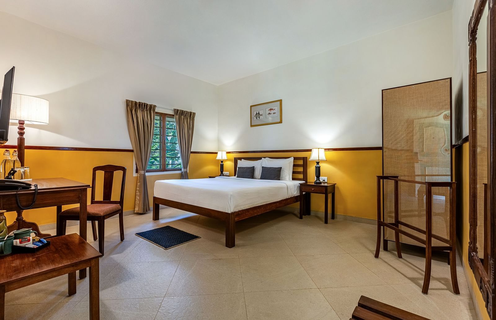 Comfortable bedroom in Pondicherry featuring a double bed, a writing desk, chairs, and a full-length mirror | Mango Hill Shallow Beach Resort ECR