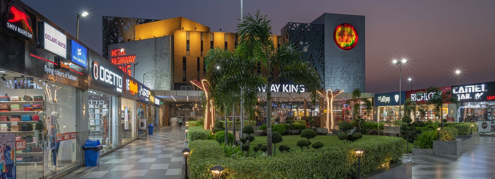 Retail and garden area near the hotel entrance with evening lights at Hotel Highway King, Bilaspur.