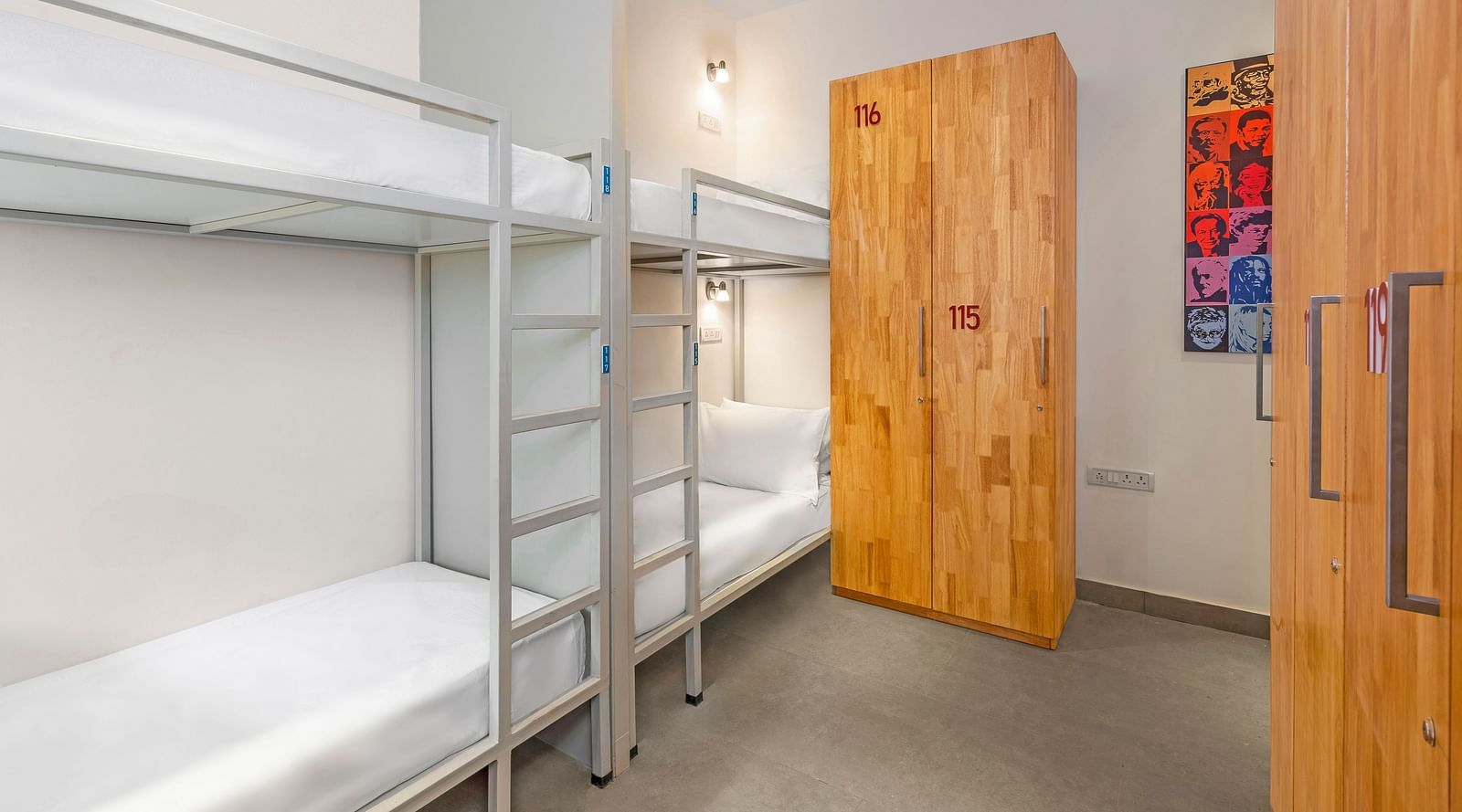 A side angle view of a dorm at Bedzzz in Varanasi features a spacious layout with a cupboard, highlighting the practical design that combines comfort and storage for guests. The inviting ambiance creates a cozy environment for relaxation and rest.