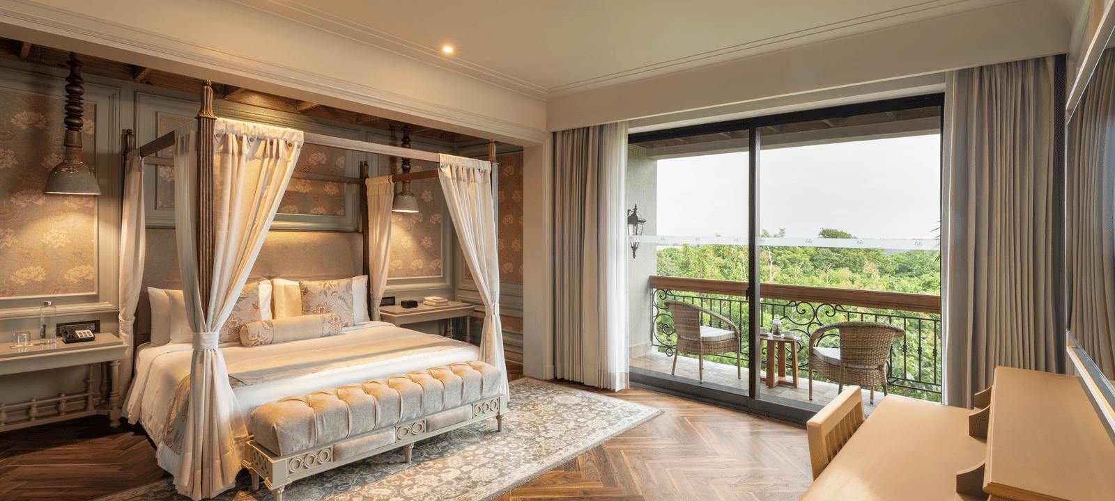 Full-view shot of the bedroom at the Evren Suite featuring wooden flooring and a balcony that opens to the verdant views of the frest at The Evren, Vagator.
