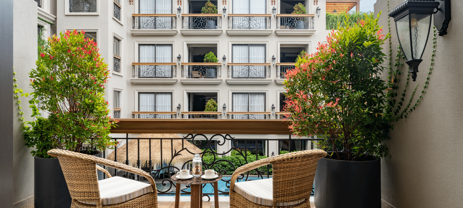 Back shot of the outdoor sit-out area in a balcony of the Premium Room overlooking the swimming pool.