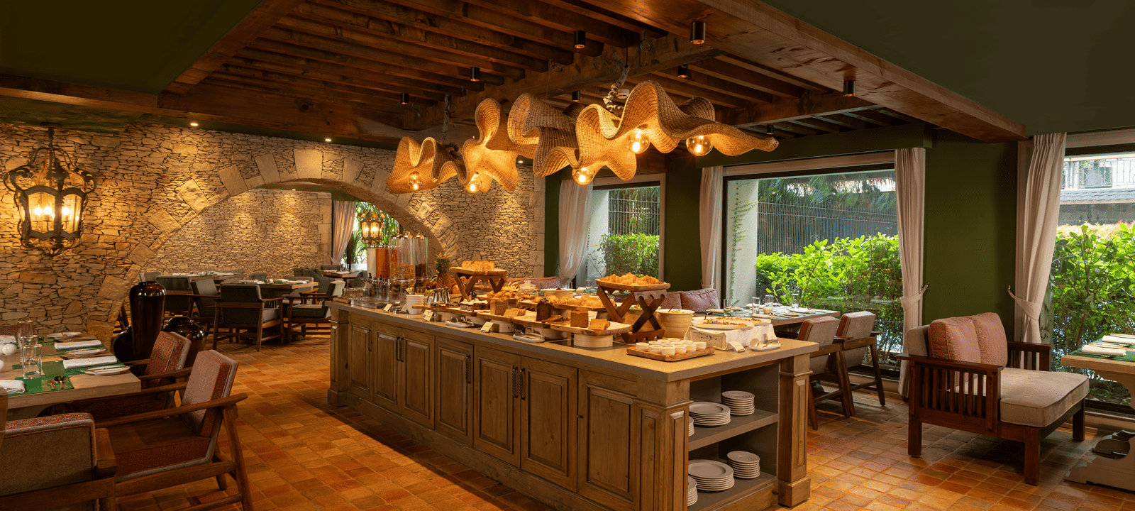 A wide-angle shot of Mila Restaurant featuring a buffet counter with crockery and cutlery stacked under it at The Evren, Vagator.