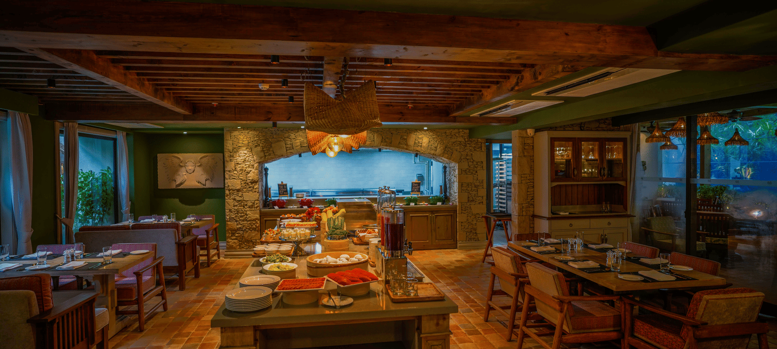 Full view of the Mila Restaurant featuring a buffet table in the middle along with well-arranged dining tables around it at The Evren, Vagator.