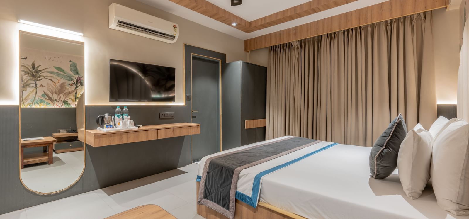 A spacious room with a king size bed, TV, mirror, desk, and the curtain spread across the window at Hotel Highway King, Jaipur.