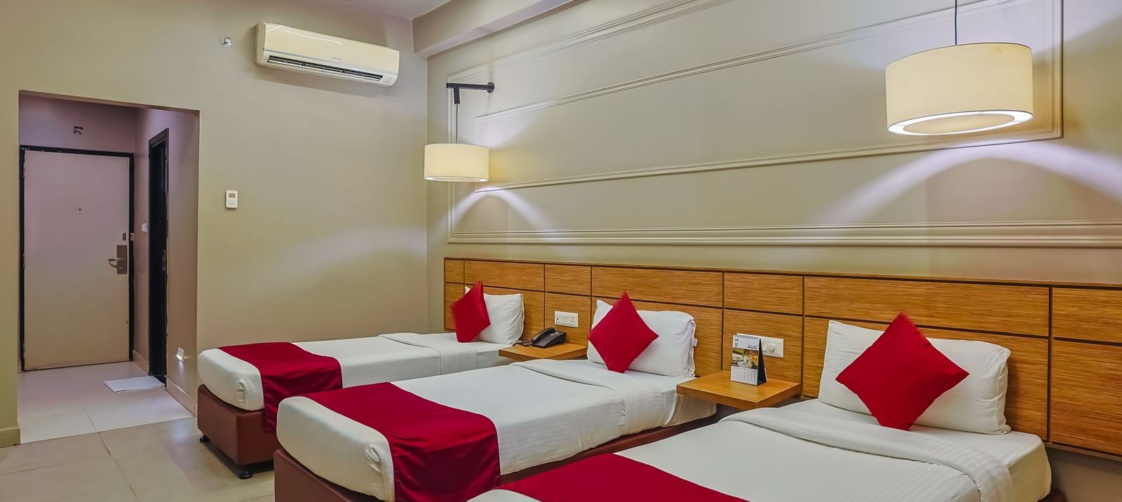 Clean and airy room with three single beds and minimalist decor at Max Hotel Prayagraj.