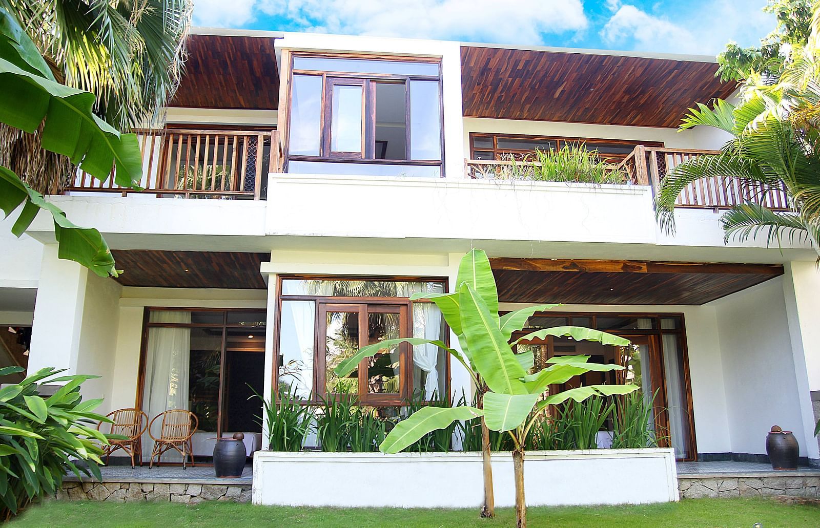 Facade view of a building with a tree and manicured lawn in front of it - Alibu Resort Nha Thrang