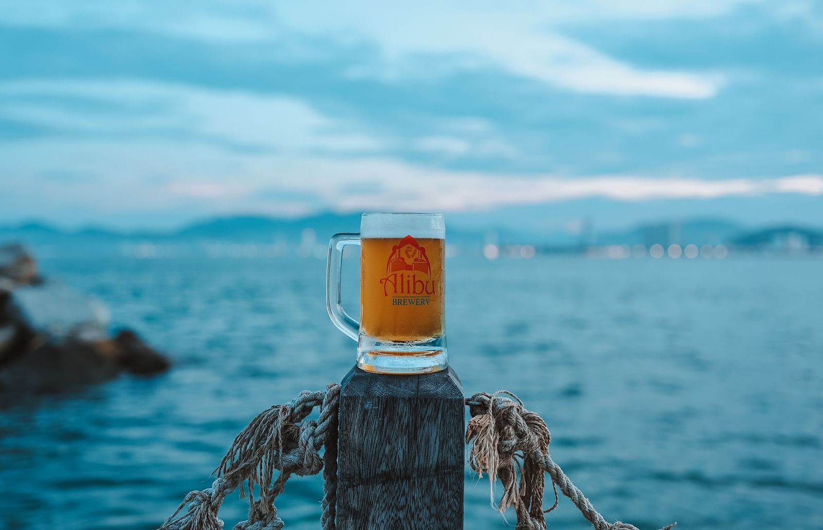 A beer placed on a wooden pillar near a serene beach - Alibu Resort Nha Trang