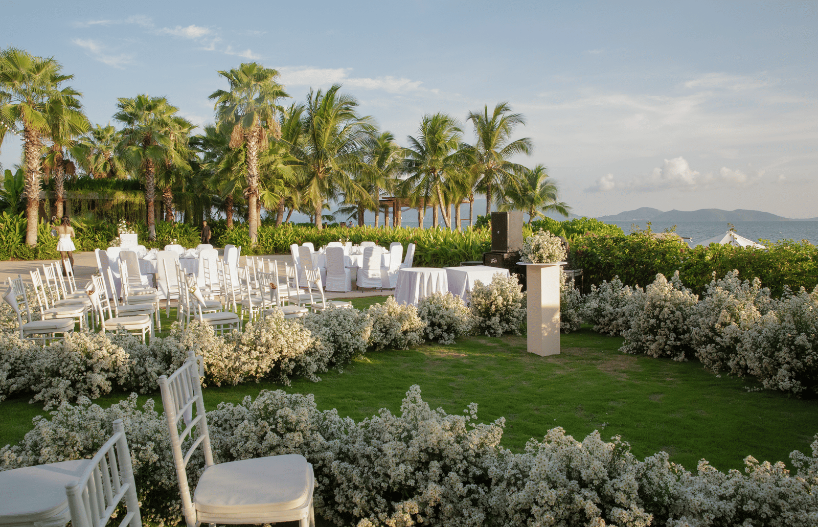 A lawn near the bay with white chairs set up for a wedding - Alibu Resort Nha Trang.