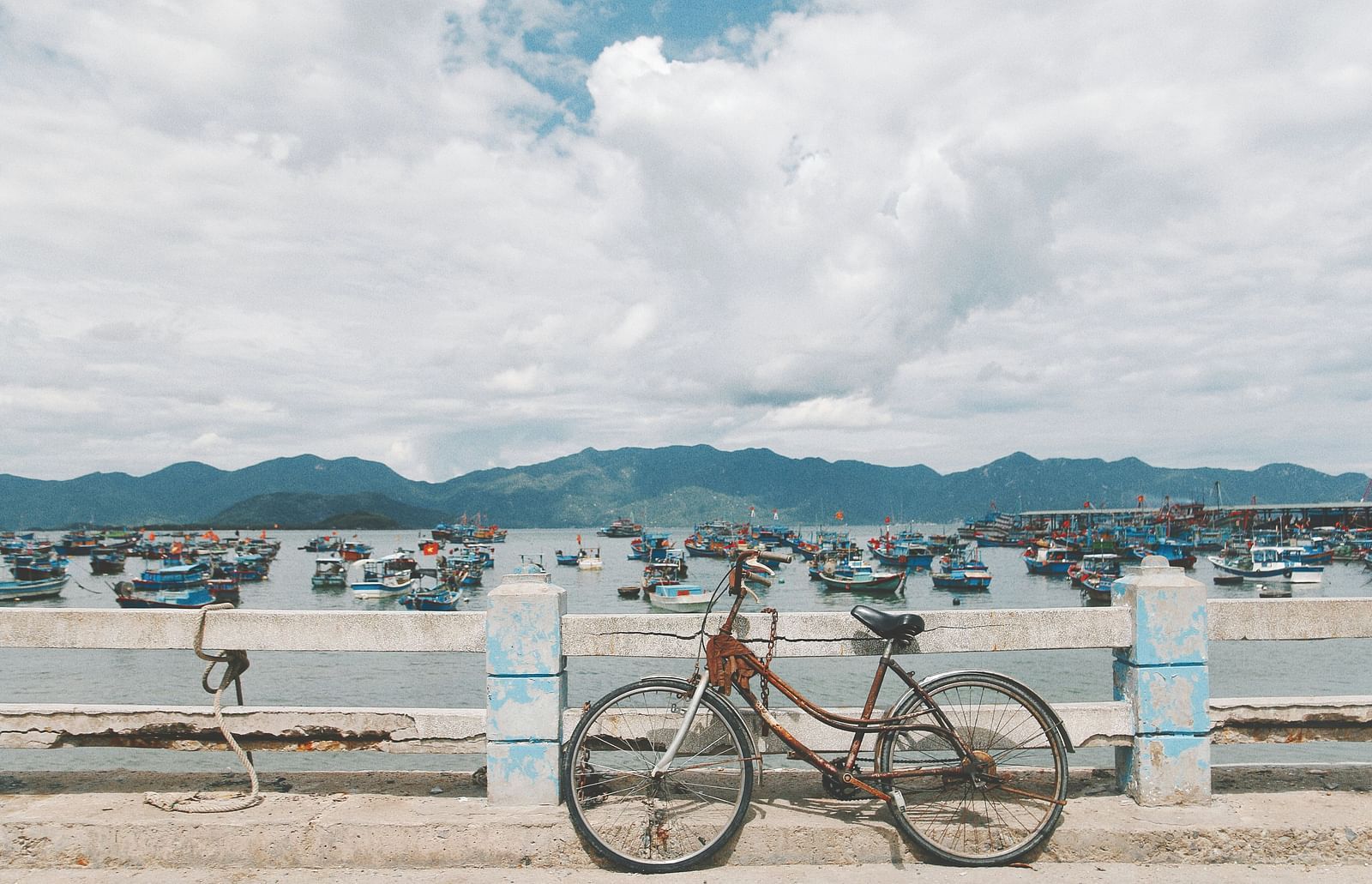 A bicycle parked on a concrete structure with fishing boats in the background in Nha Trang