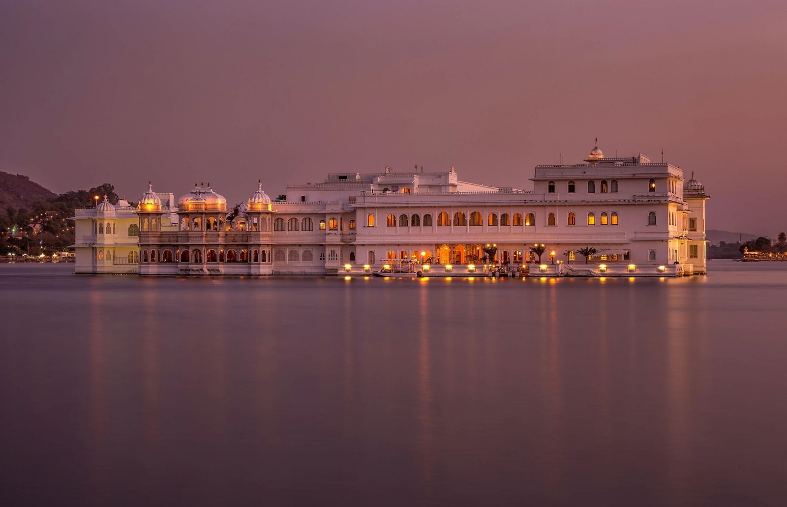  A large building sits in water. Lights illuminate the structure. 