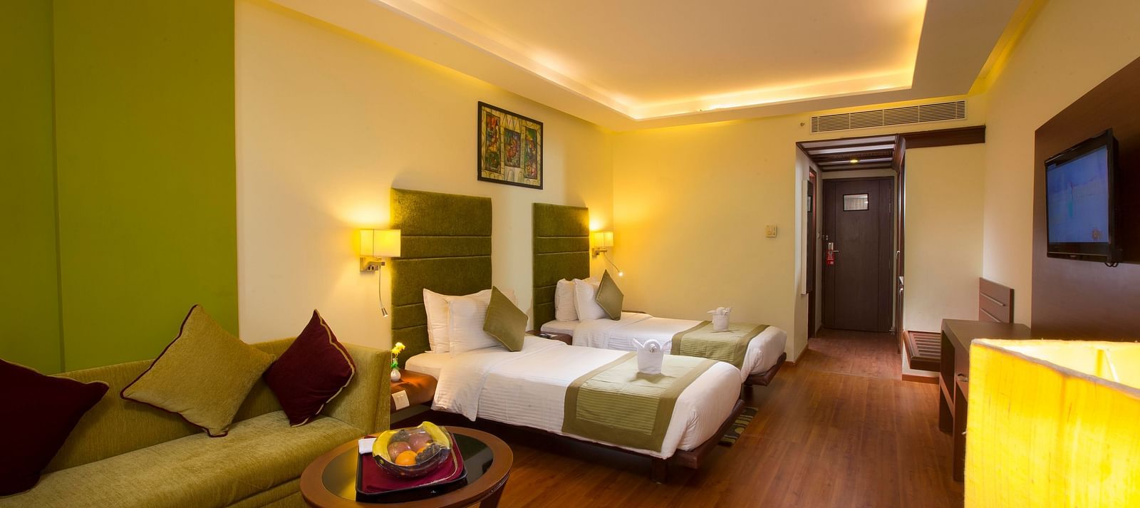 Superior Room featuring twin beds, sofa and a television at Hotel Atithi - TGI Grand, Pondicherry