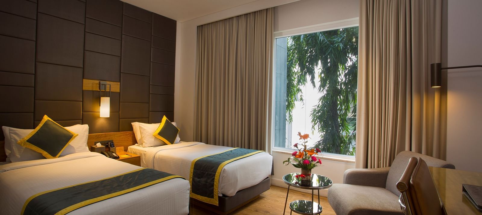 a bedroom with the curtains drawn out offering views of the city with two single beds and a sofa  - Hotel Fountain Tree By TGI - JP Nagar, Bangalore