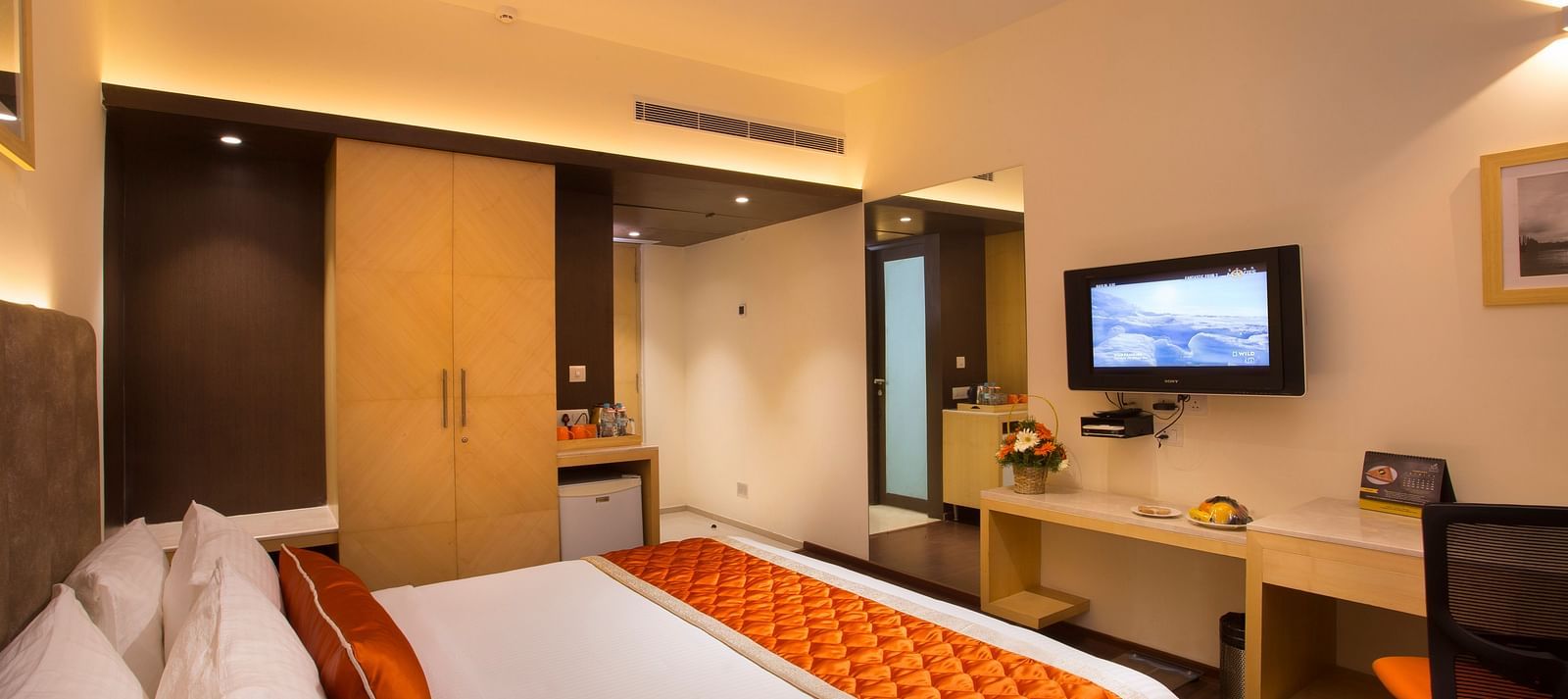 A comfortable hotel room with modern amenities, a large bed, a TV and a work desk with a chair - Hotel Langford Keys by TGI, Shanti Nagar