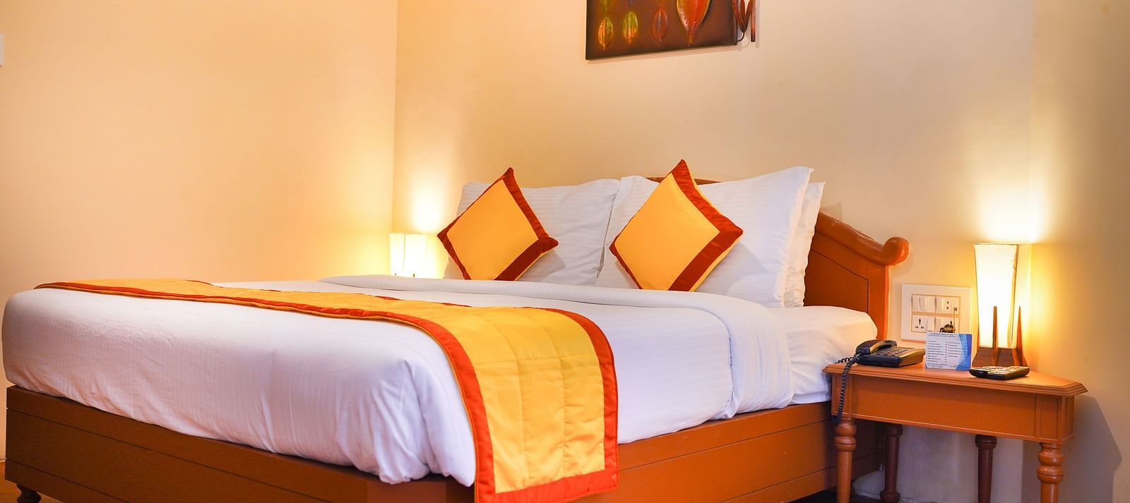 a view of a plush bed with yellow and orange cover and pillows at La Montana By TGI, Ooty