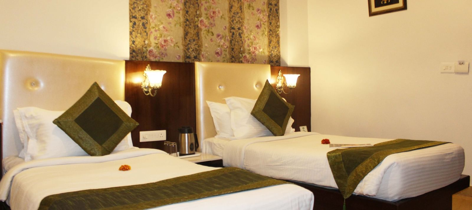 A hotel room with two beds, green runners, floral wallpaper and a wooden headboard - TGI Apple Inn, Jaipur 