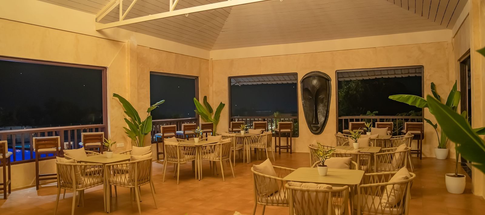 An interior of a restaurant with chairs and square tables arranged in sets - Crescent Resort, Goa